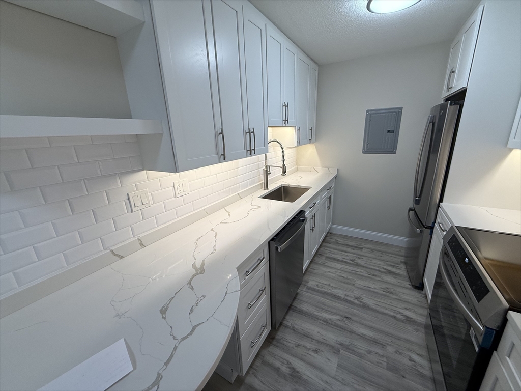 566 Commonwealth Avenue, Unit 308 Boston, MA 02215 - Photo 10 of 14 a kitchen with granite countertop a sink a stove oven and cabinets