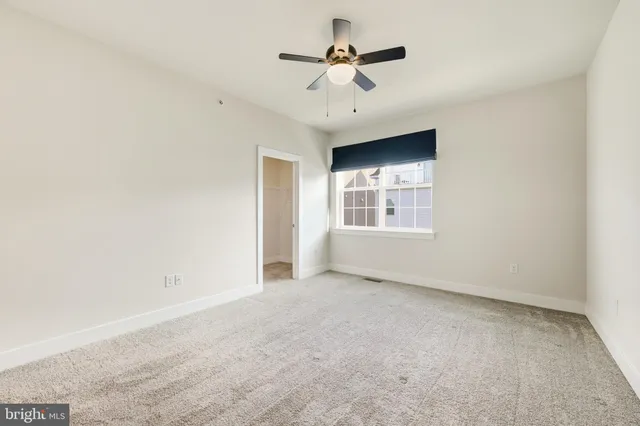 an empty room with windows and ceiling fan