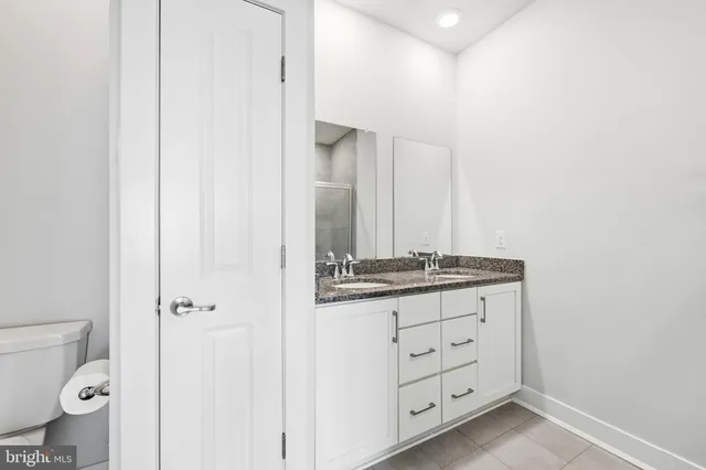 a bathroom with a granite countertop sink and a toilet