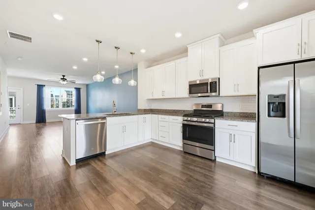 a large kitchen with white cabinets stainless steel appliances and a center island