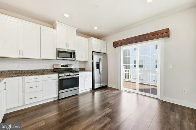 a kitchen with stainless steel appliances a stove top oven a refrigerator a sink and a hard wood floors