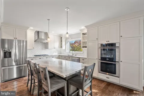 a kitchen with kitchen island a dining table chairs stainless steel appliances and cabinets
