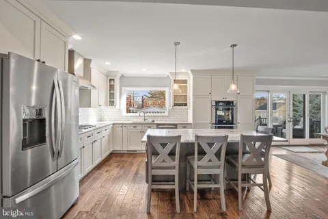 a kitchen with stainless steel appliances granite countertop a dining table chairs refrigerator and microwave