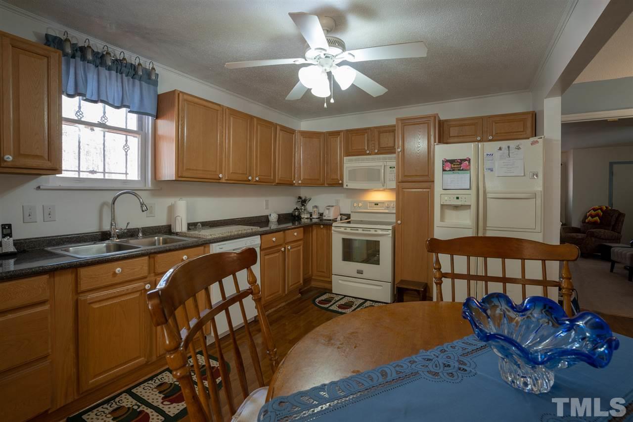 3411 Freeman Road Durham, NC 27703 - Photo 9 of 24 a kitchen with stainless steel appliances granite countertop a stove a sink dishwasher and a refrigerator with wooden floor