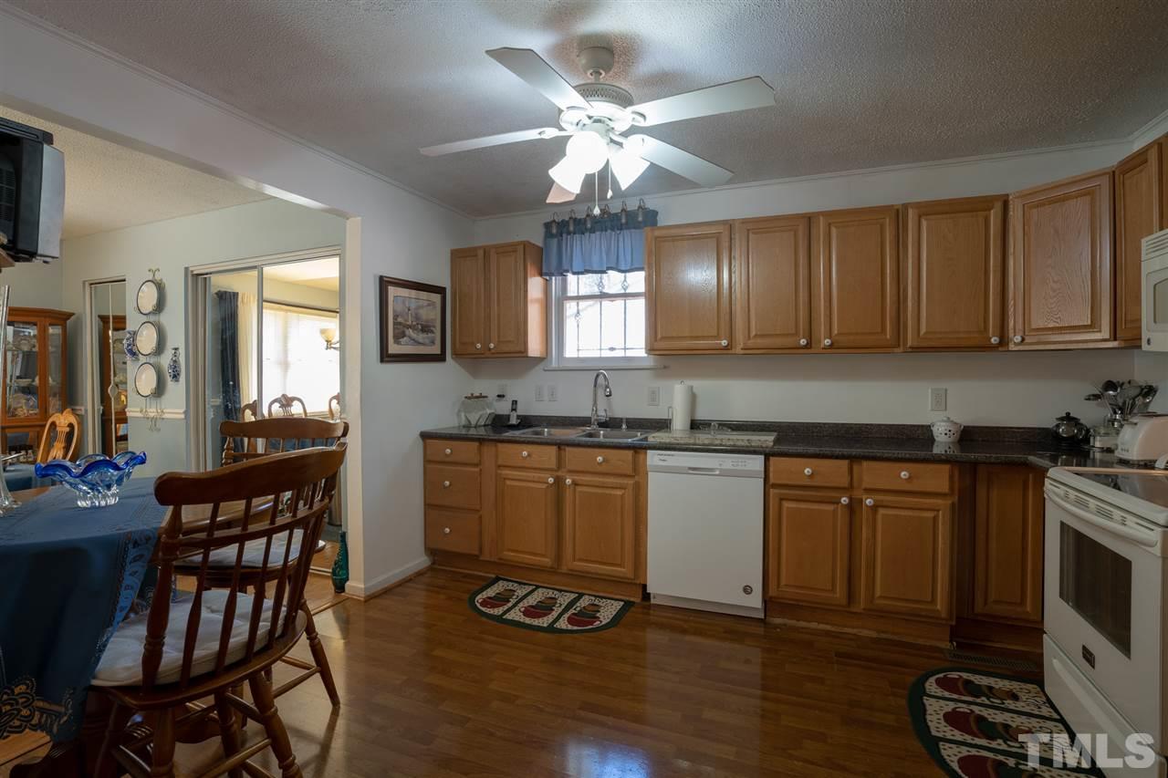 3411 Freeman Road Durham, NC 27703 - Photo 10 of 24 a kitchen with granite countertop wooden floors cabinets a dining table and appliances