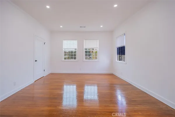 a view of an empty room with wooden floor and windows