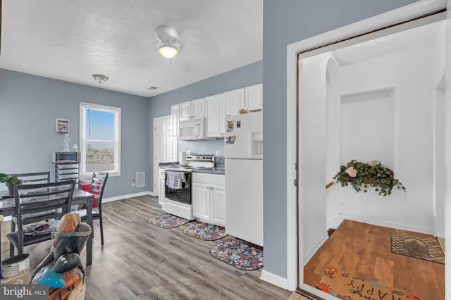 a kitchen with stainless steel appliances granite countertop a stove a sink dishwasher and a refrigerator with white cabinets