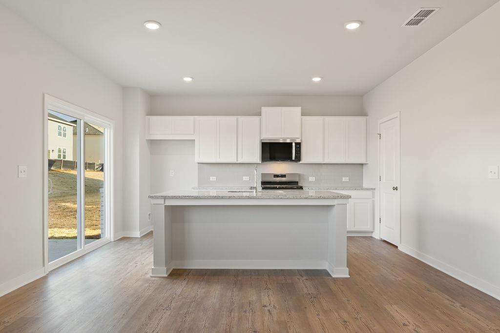 542 Arborston Way Jefferson, GA 30549 - Photo 20 of 28 a kitchen with stainless steel appliances a sink stove and wooden floor