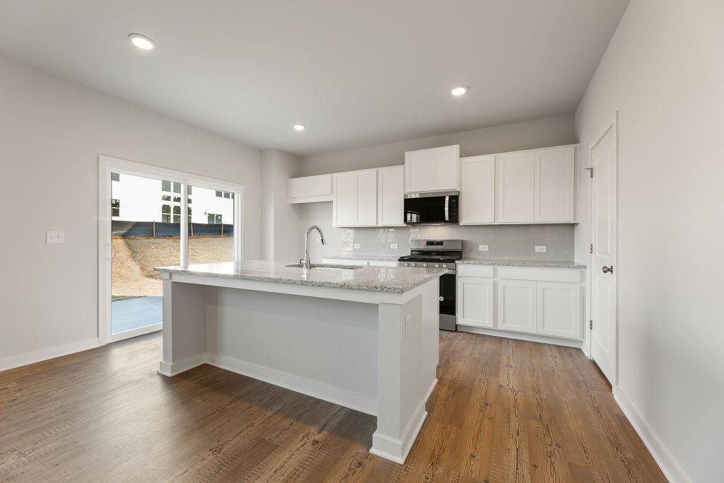 542 Arborston Way Jefferson, GA 30549 - Photo 23 of 28 a kitchen with stainless steel appliances granite countertop a stove a sink and a microwave