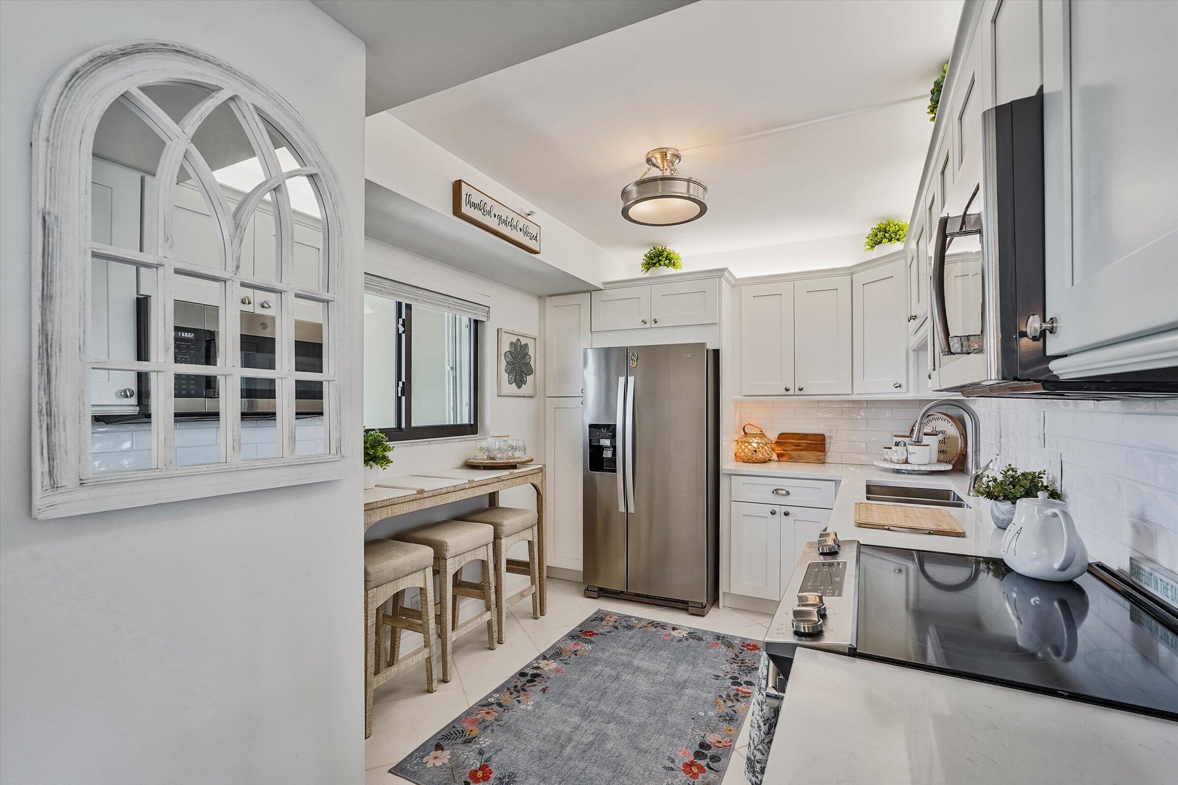 400 Ocean Trail Way, Unit 703 Jupiter, FL 33477 - Photo 19 of 63 a kitchen with stainless steel appliances granite countertop a refrigerator a stove and a sink with wooden floor