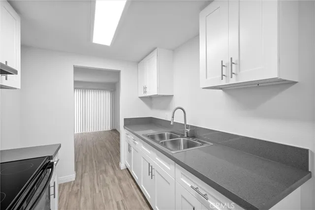 a kitchen with granite countertop a sink a stove and cabinets