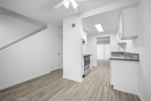 a kitchen with white cabinets and wooden floor