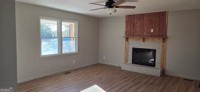 a view of an empty room with window and wooden floor