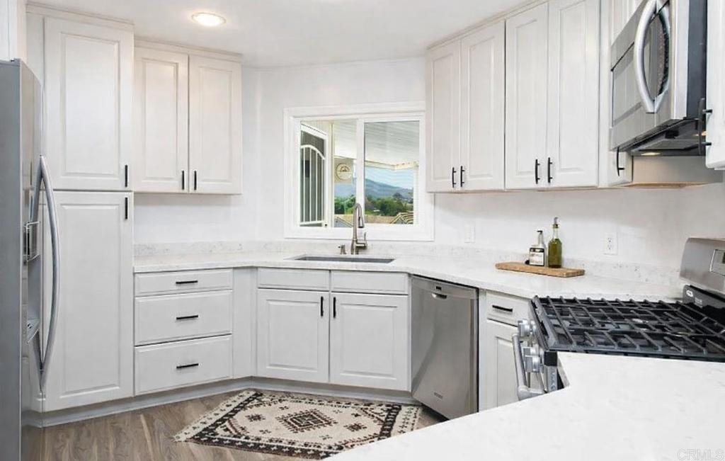 a kitchen with stainless steel appliances a white stove top oven and white cabinets