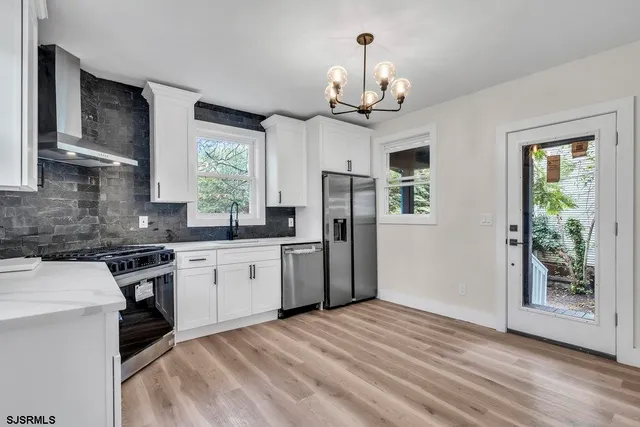 a kitchen with stainless steel appliances granite countertop a stove a sink dishwasher a refrigerator and a fireplace with wooden floor