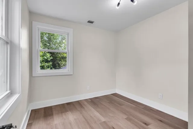 an empty room with wooden floor and windows