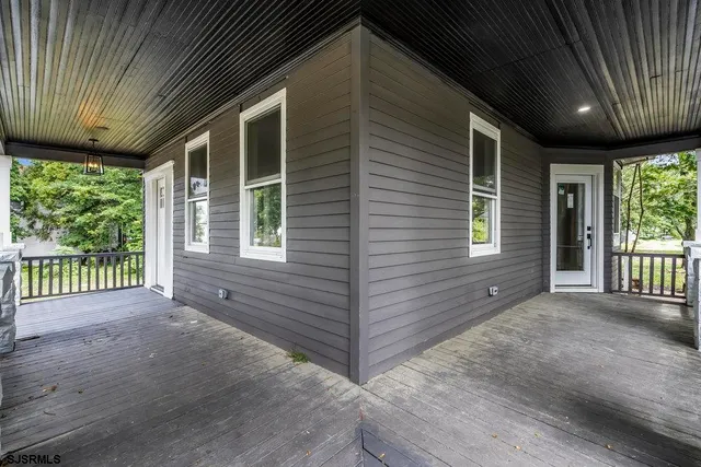 a view of a porch with wooden floor and roof with a garden