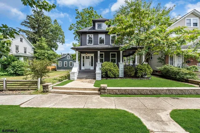 a front view of a house with a yard and potted plants
