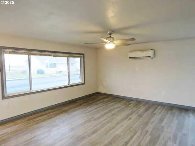 an empty room with wooden floor fan and windows
