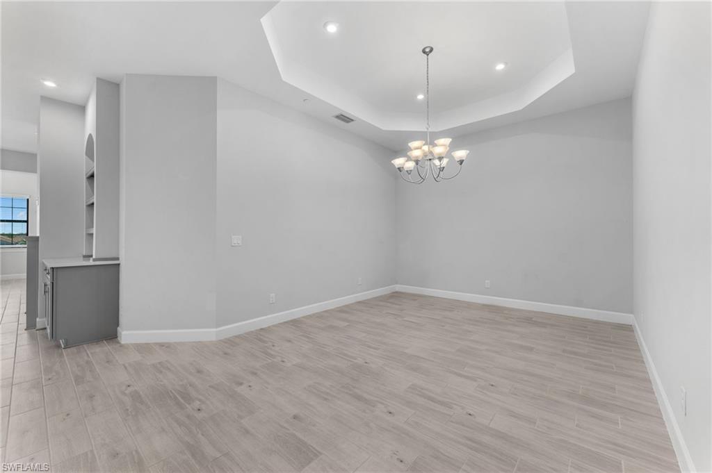 15244 Zeno Way, Unit 201 Naples, FL 34114 - Photo 18 of 48 en empty room with wooden floor and chandelier