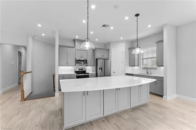 a large kitchen with kitchen island a sink counter space stainless steel appliances and a fireplace