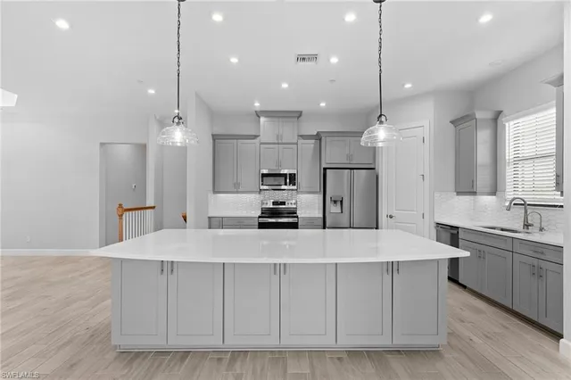 a large kitchen with kitchen island a stove a sink a center island and wooden floor