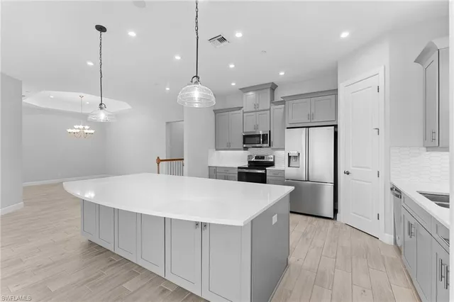 a large kitchen with stainless steel appliances lots of counter space space refrigerator and a wooden floor