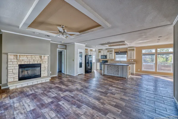 a view of an empty room with wooden floor fireplace and a window