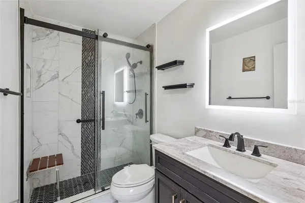 a bathroom with a granite countertop sink toilet and shower