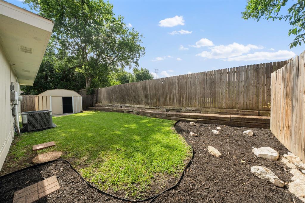 310 Valley Spring Drive Arlington, TX 76018 - Photo 24 of 24 Backyard featuring a manicured lawn, full privacy fencing, and a detached storage shed