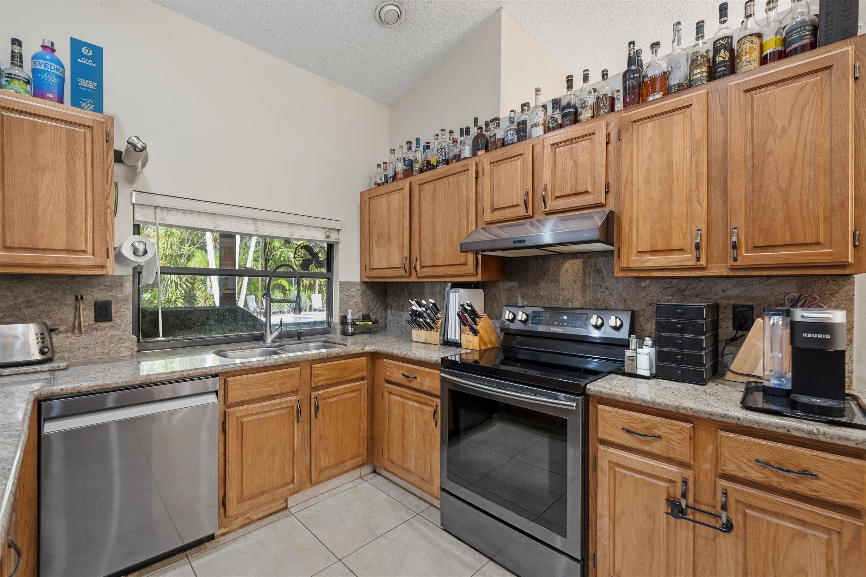 7169 154th Road North Palm Beach Gardens, FL 33418 - Photo 13 of 62 a kitchen with granite countertop a sink stainless steel appliances and cabinets