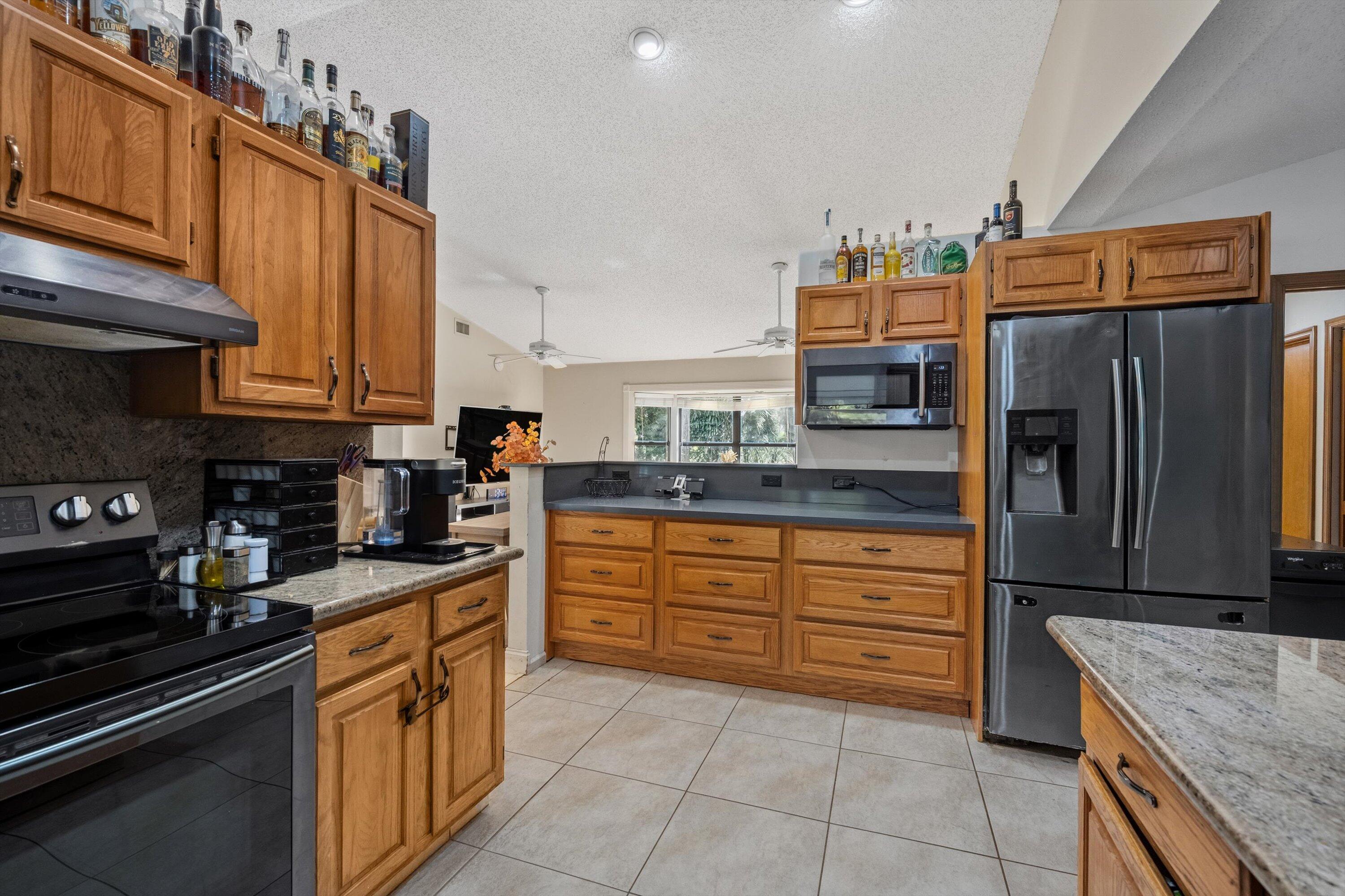 7169 154th Road North Palm Beach Gardens, FL 33418 - Photo 16 of 62 a kitchen with stainless steel appliances granite countertop a refrigerator and a stove top oven