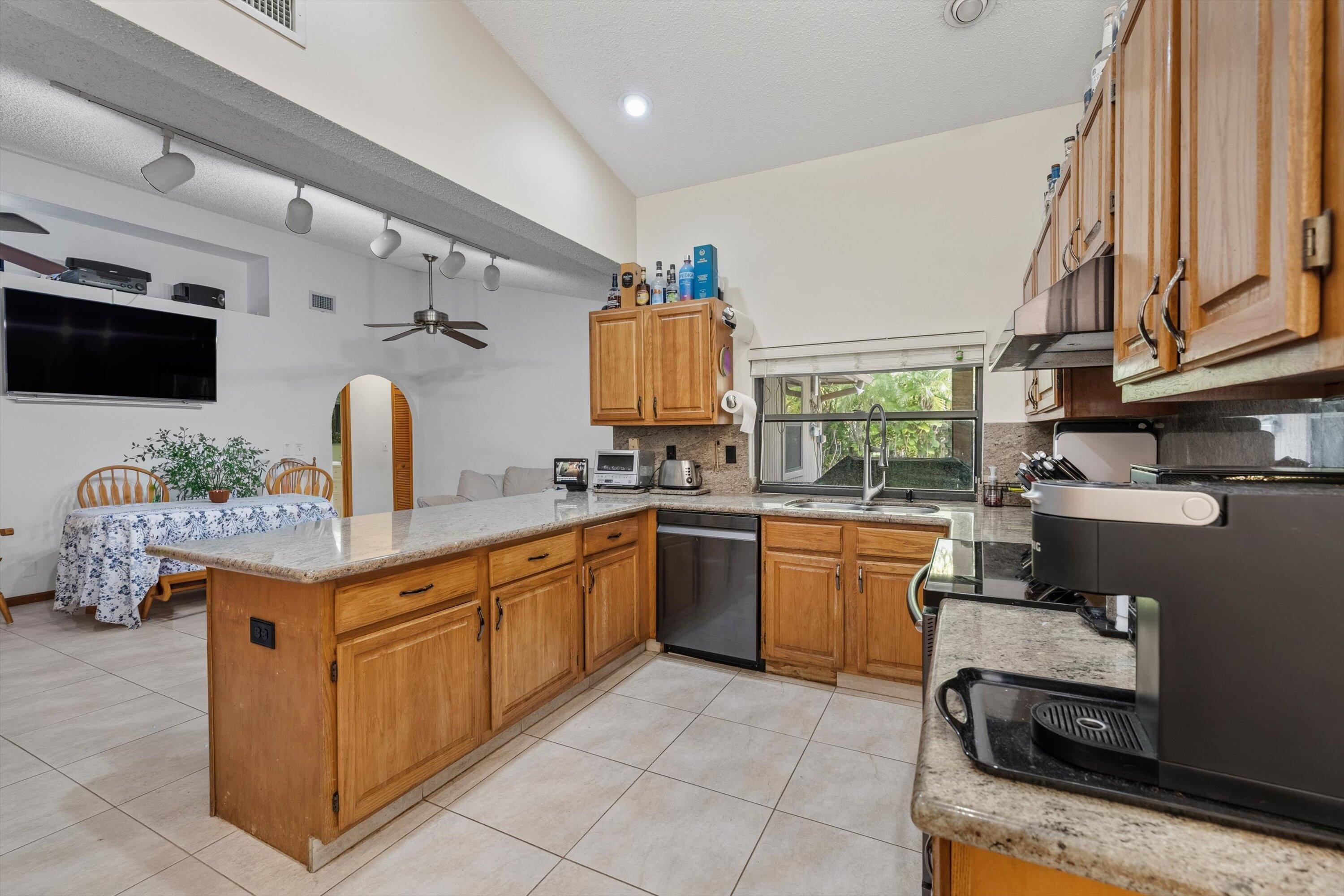 7169 154th Road North Palm Beach Gardens, FL 33418 - Photo 19 of 62 a kitchen with granite countertop a sink stove and cabinets