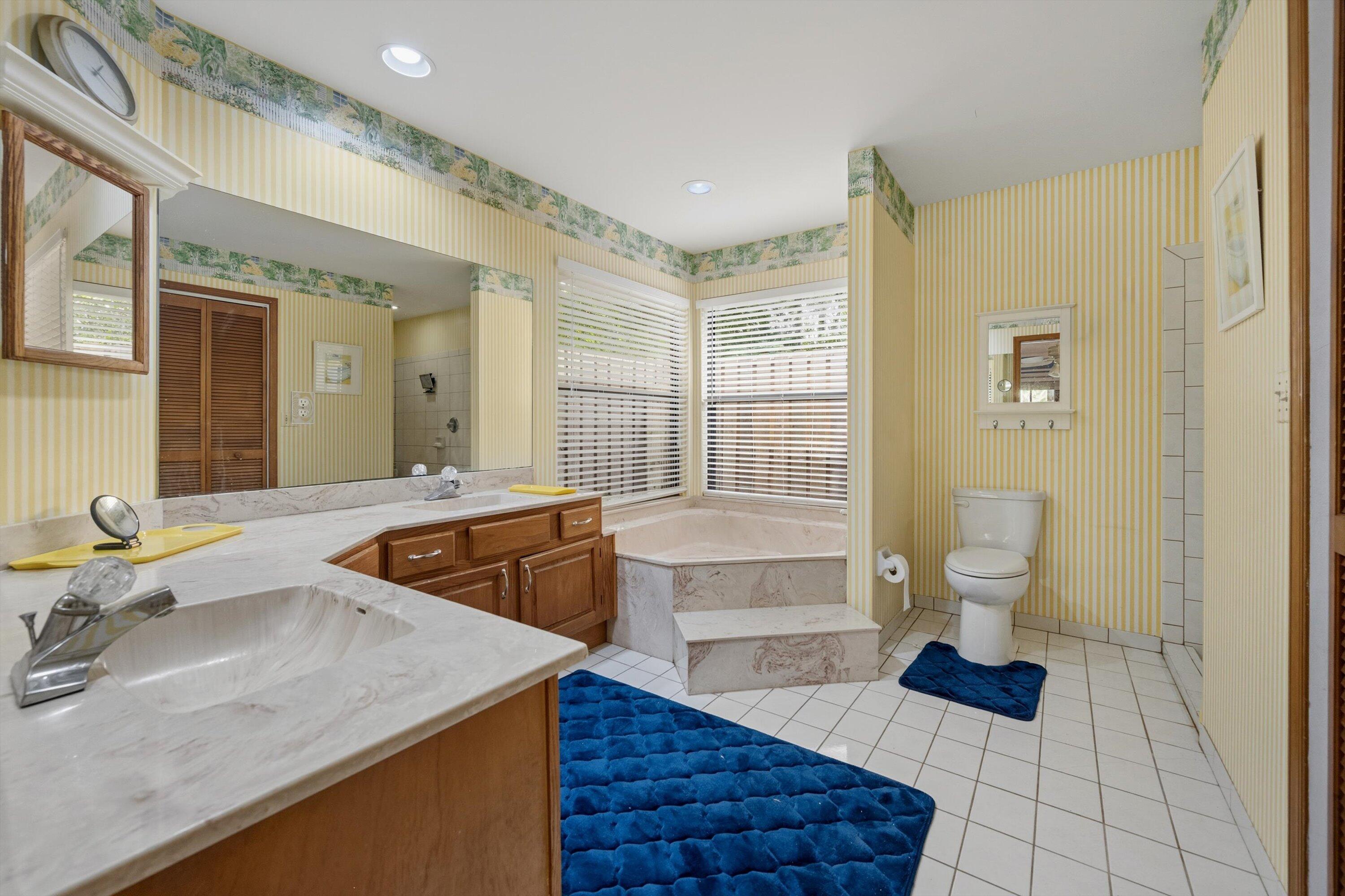 7169 154th Road North Palm Beach Gardens, FL 33418 - Photo 22 of 62 a bathroom with a granite countertop sink a toilet a mirror and shower