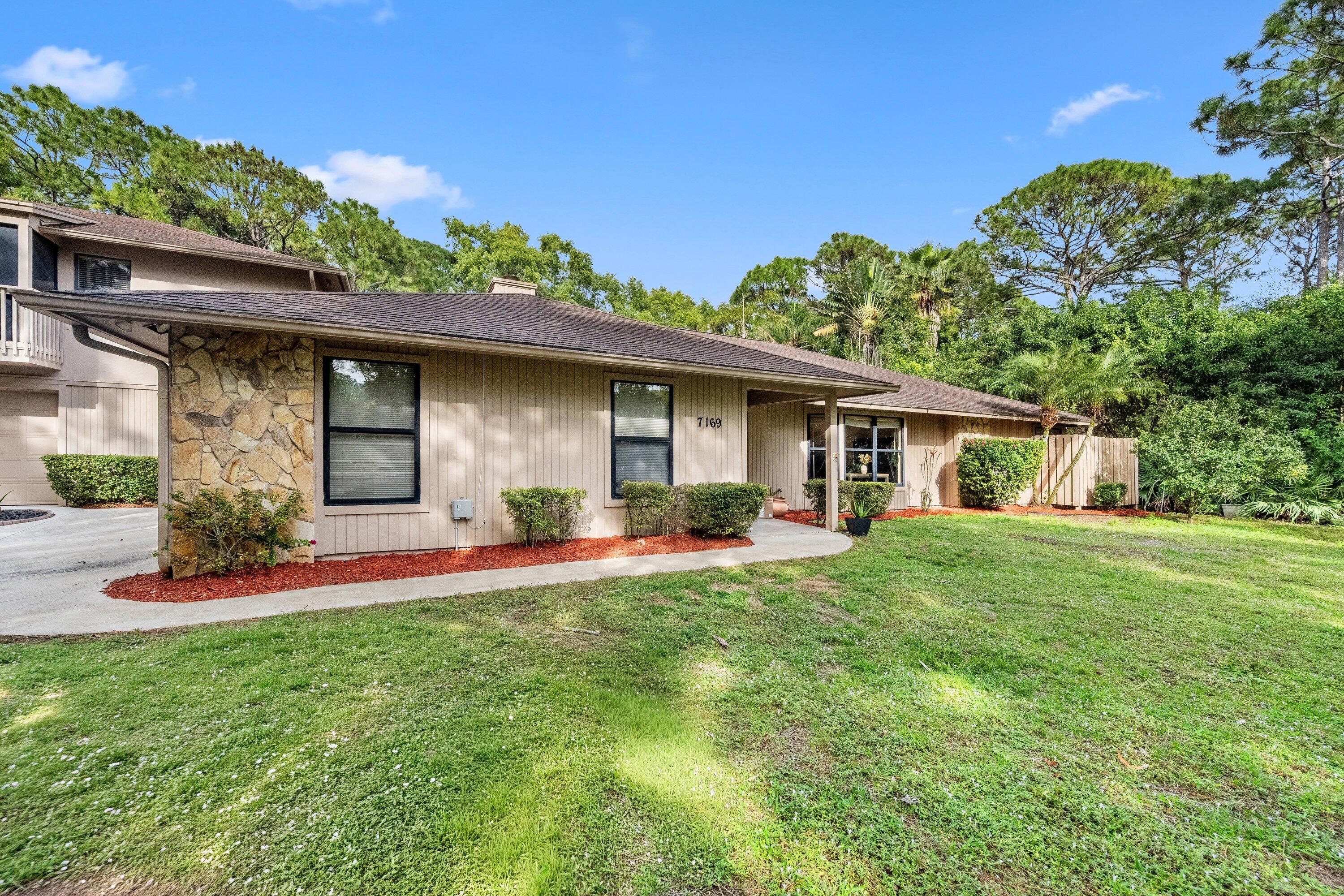 7169 154th Road North Palm Beach Gardens, FL 33418 - Photo 4 of 62 a front view of a house with a yard and trees