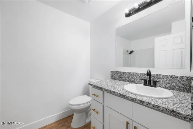 a bathroom with a granite countertop sink and a toilet