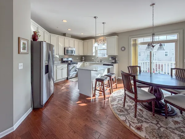 a kitchen with stainless steel appliances a dining table chairs stove refrigerator and cabinets