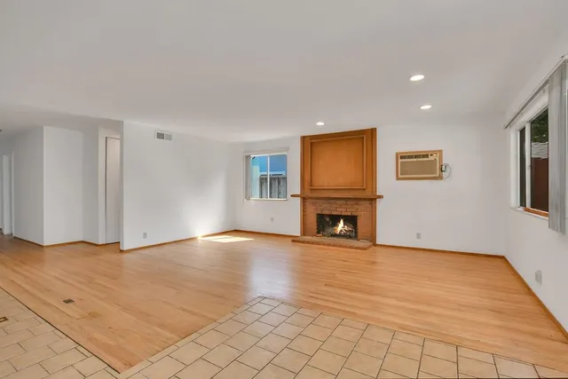 a view of empty room with wooden floor and fireplace