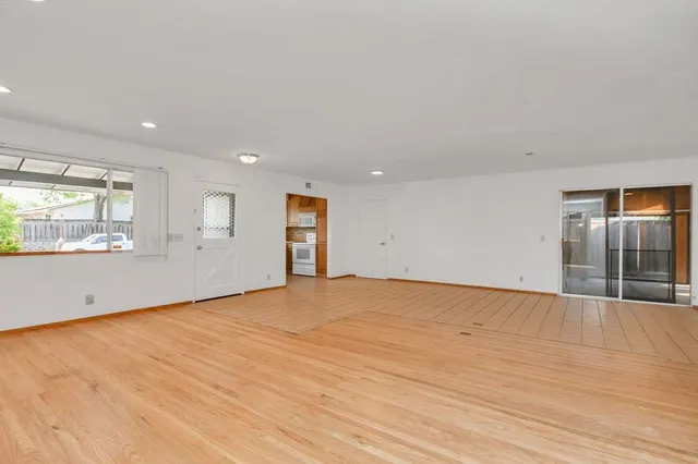 a view of an empty room with wooden floor and windows