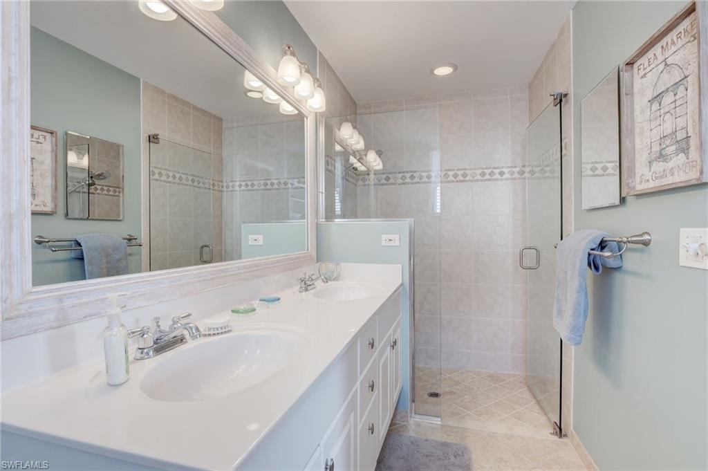 280 Robin Hood Circle, Unit 102 Naples, FL 34104 - Photo 10 of 24 a bathroom with a double vanity sink mirror and shower