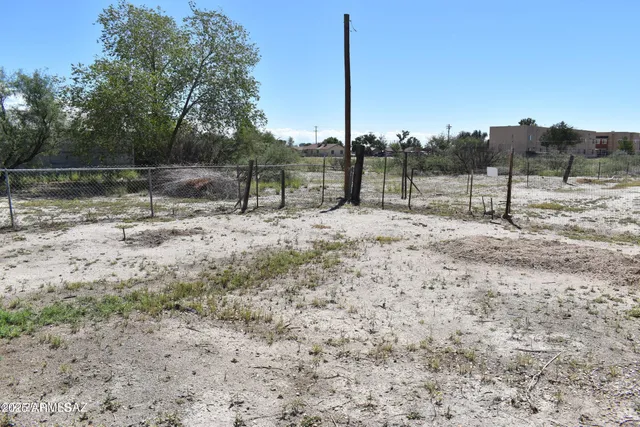 a view of dirt field with trees in the background