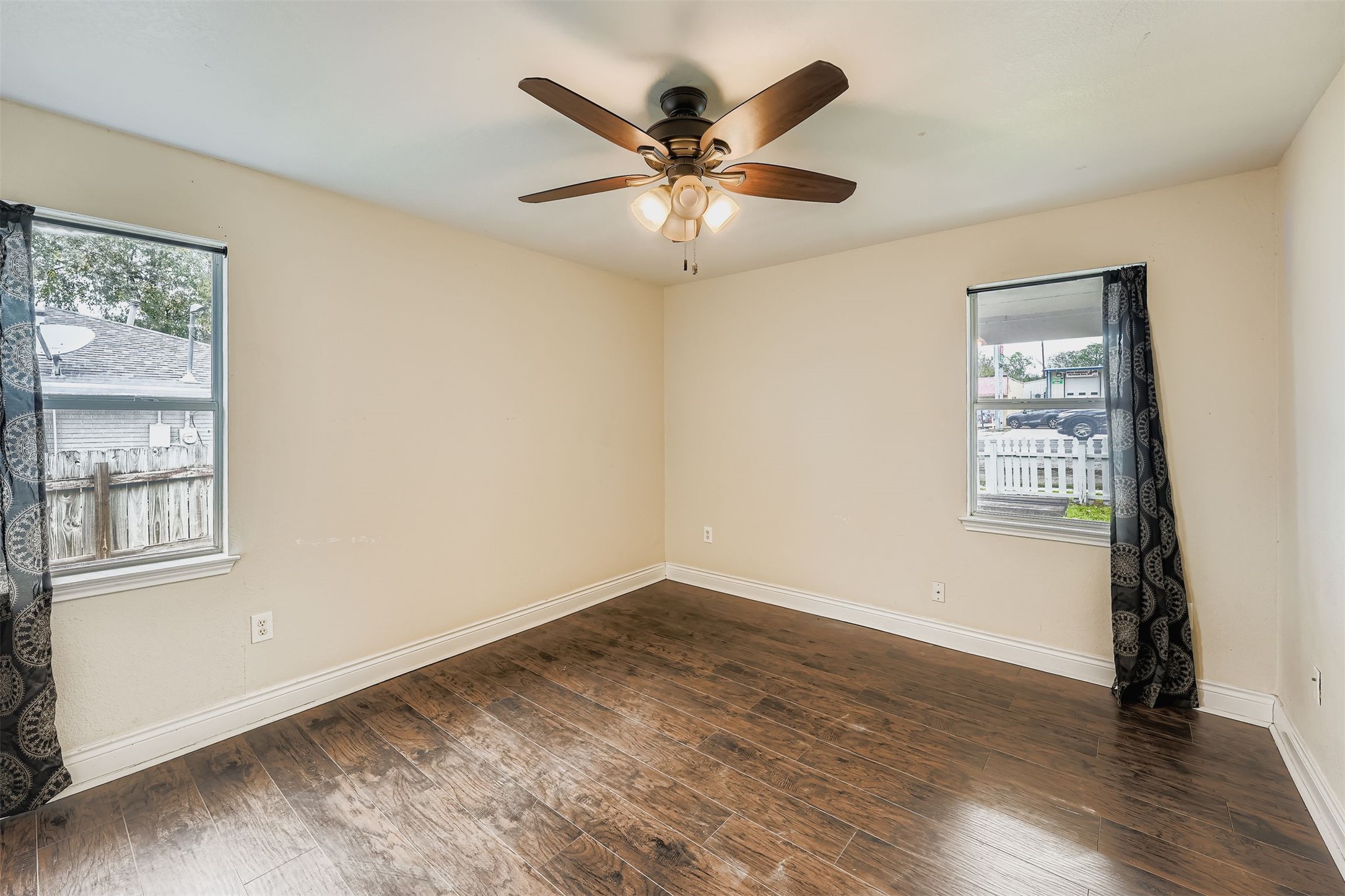 304 South Main Street Elgin, TX 78621 - Photo 21 of 25 Empty room featuring dark wood-type flooring, healthy amount of natural light, and a ceiling fan