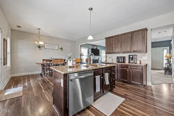 a kitchen with stainless steel appliances kitchen island granite countertop a table chairs stove and refrigerator