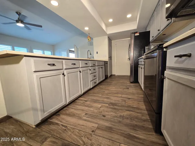 a large kitchen with lot of cabinets and wooden floor