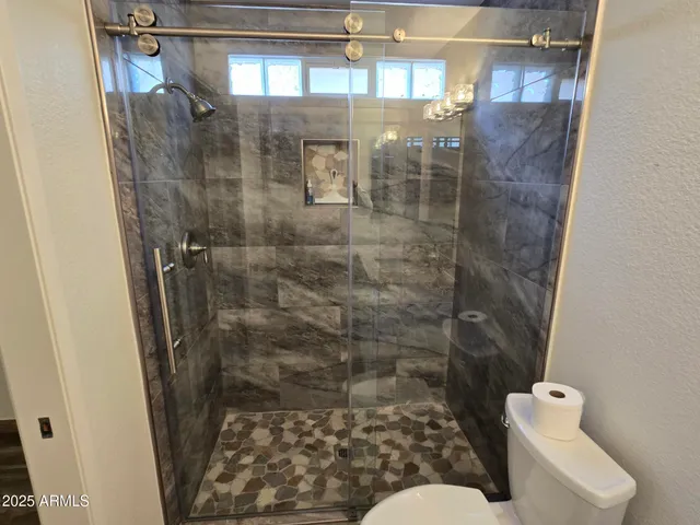 a bathroom with a sink a toilet a mirror and shower