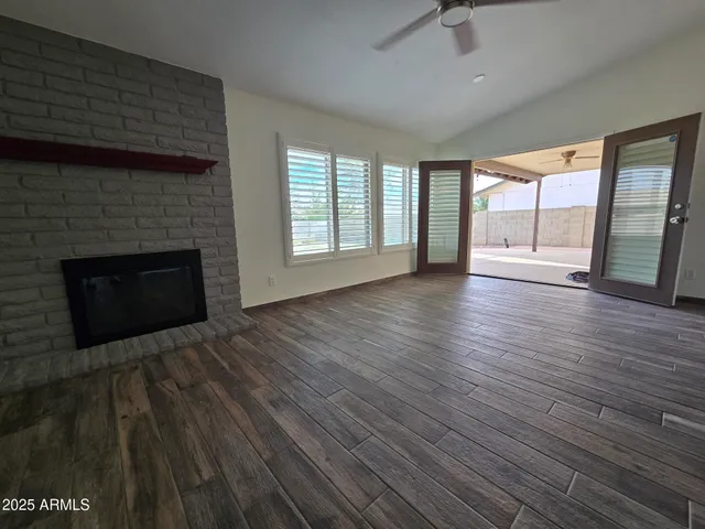an empty room with wooden floor fireplace and windows