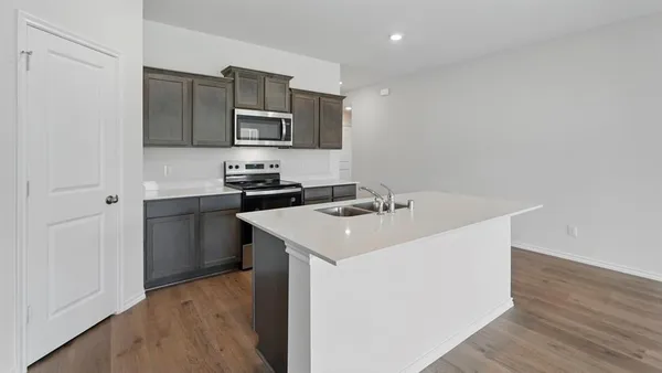 a kitchen with stainless steel appliances a sink a stove a microwave a sink and cabinets