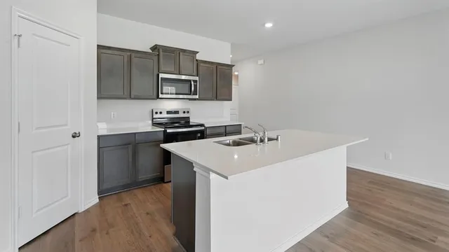 a kitchen with stainless steel appliances a sink a stove a microwave a sink and cabinets