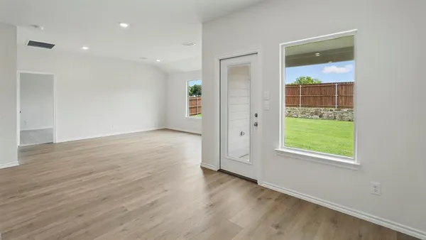 an empty room with wooden floor and windows