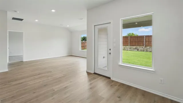 an empty room with wooden floor and windows